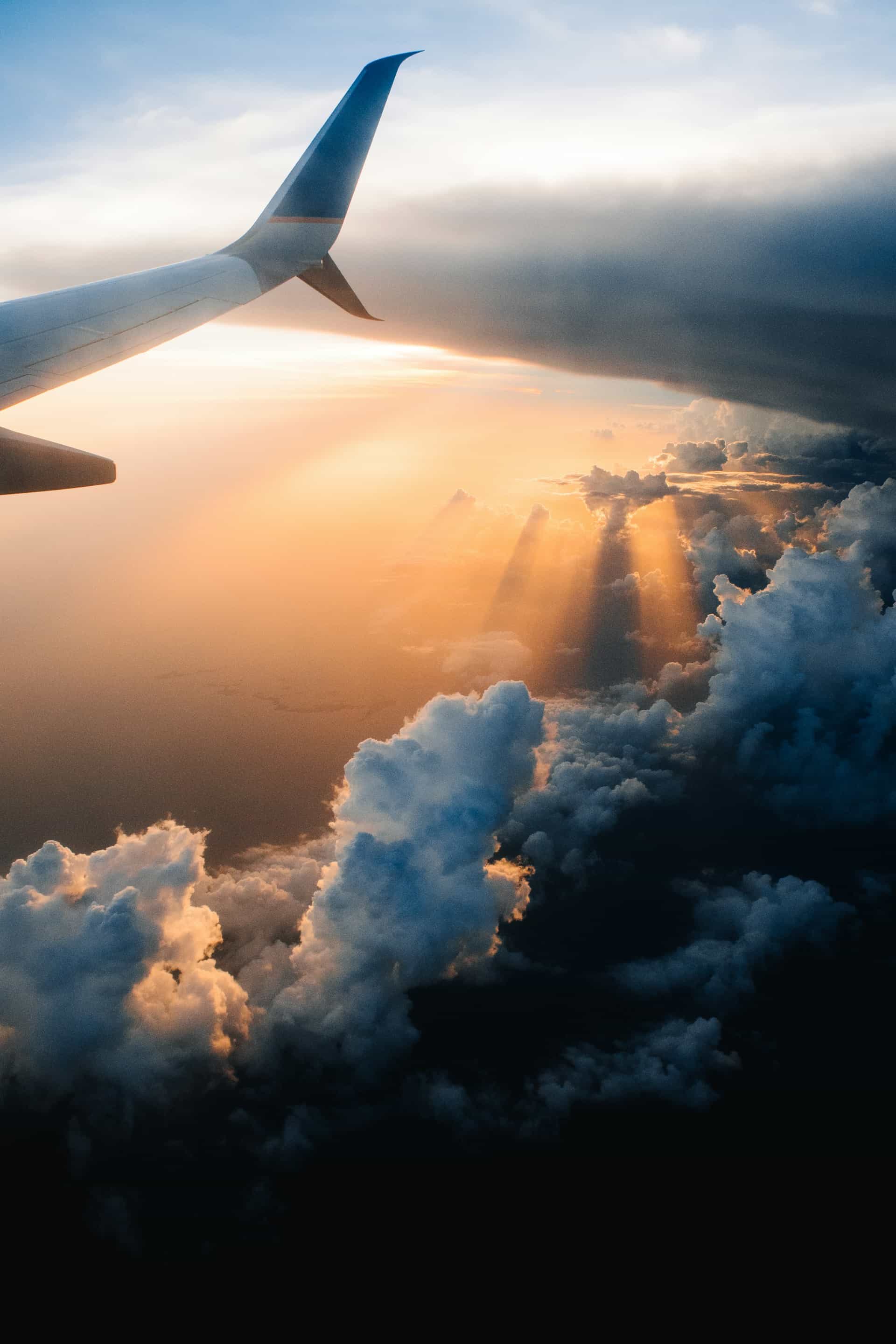 Airplane wing above glowing clouds during a beautiful takeoff flight